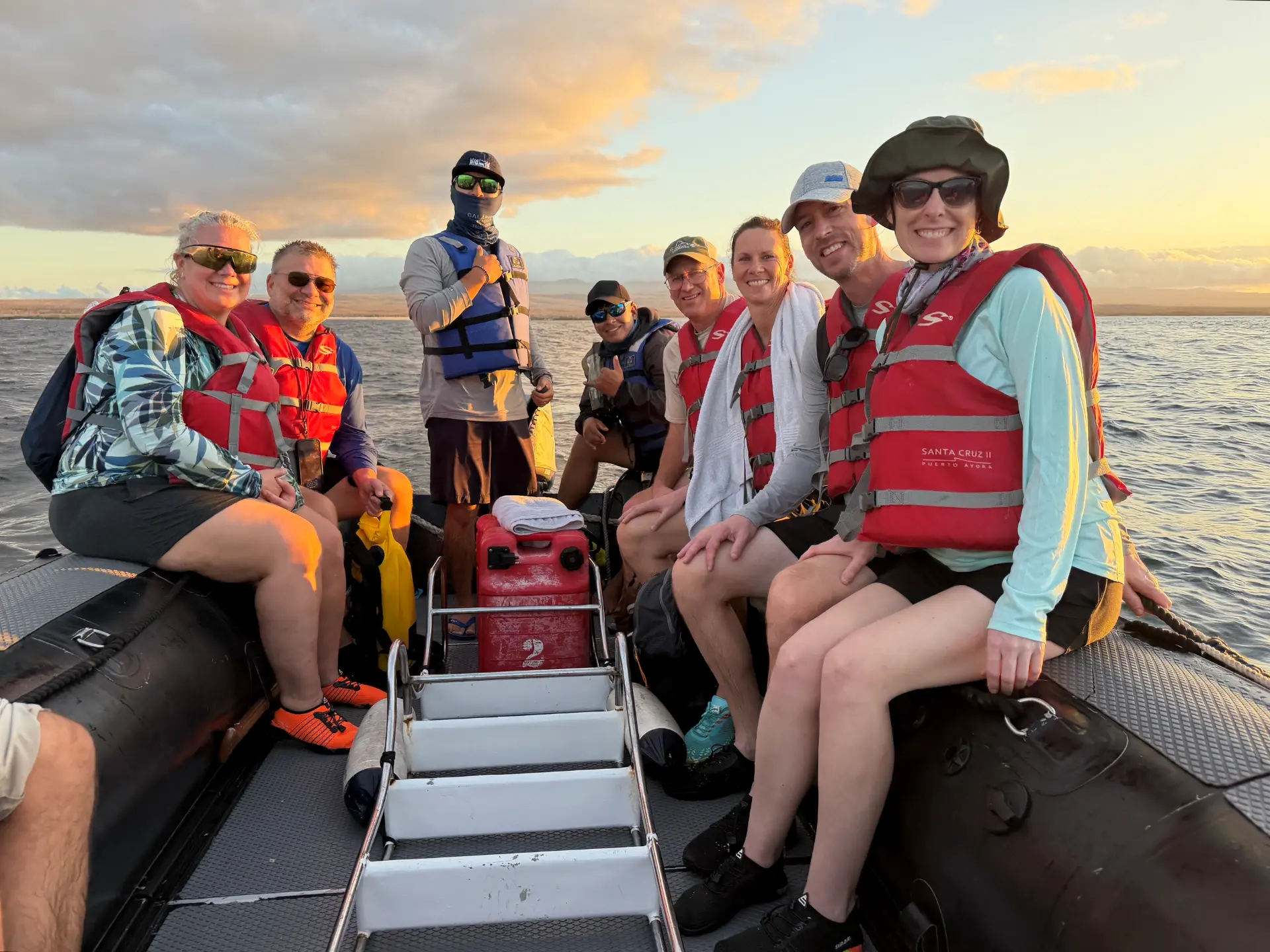 A group of travelers in red life jackets riding a zodiac at sunset in the Galápagos Islands